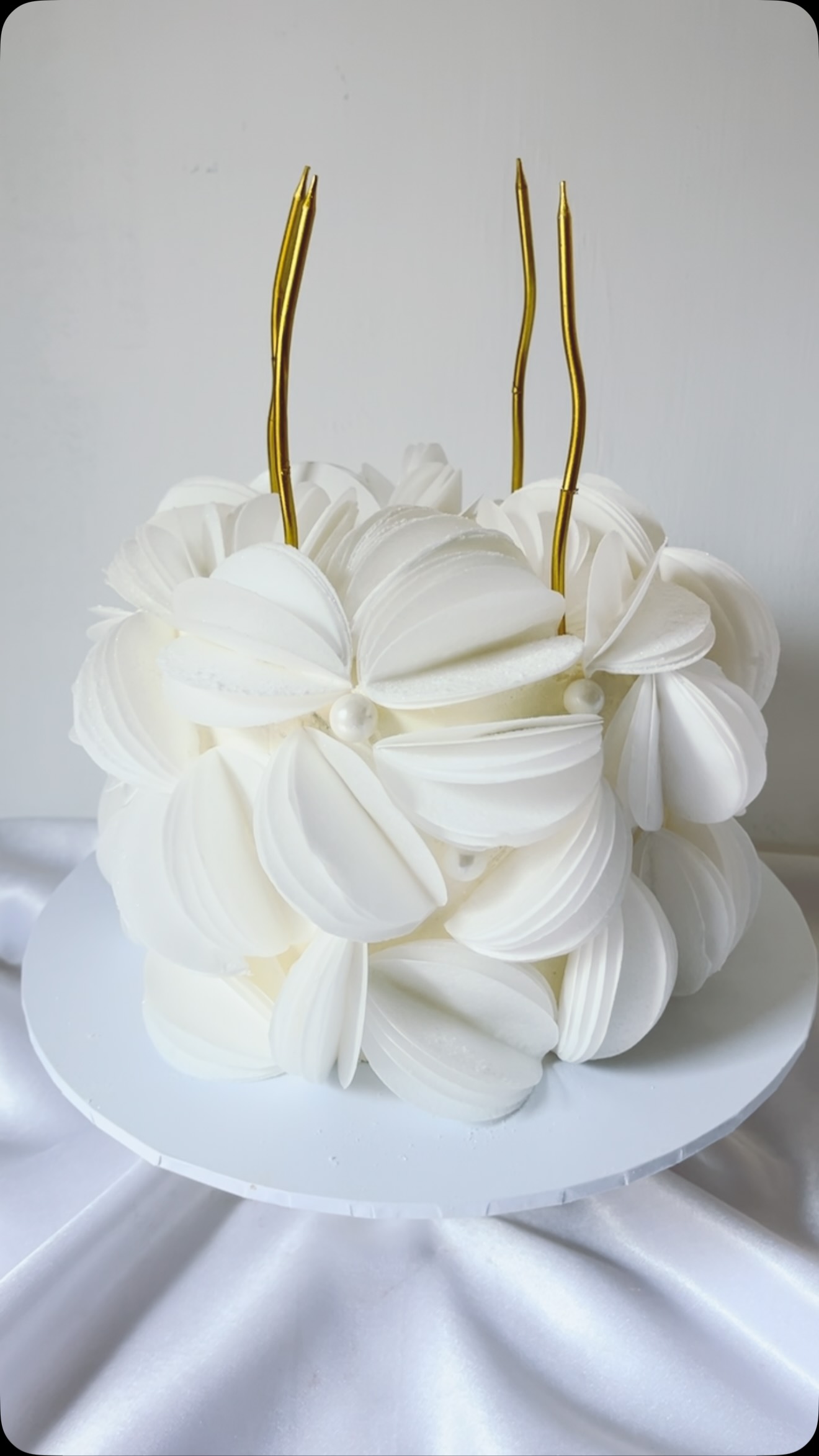 An all-white cake decorated with bows and gold detail